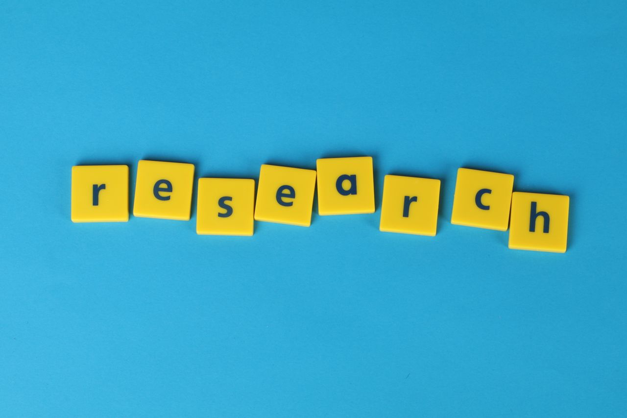 about-04 Yellow letter tiles spell the word 'research' on a vibrant blue surface, perfect for educational themes.