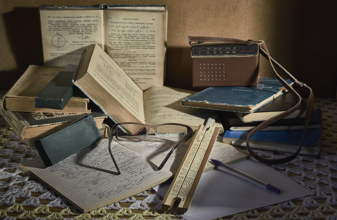 services-06 Still life of a classic study setting with vintage books, glasses, slide rule, and an old analog radio.